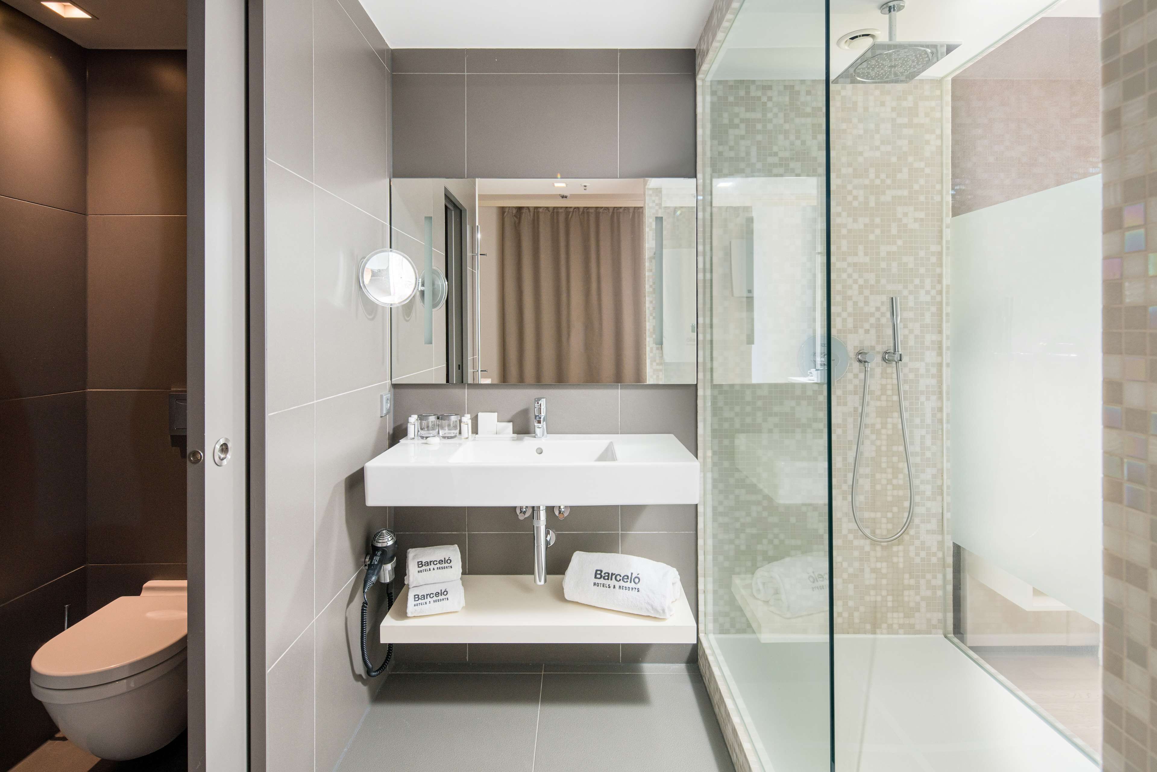 A modern bathroom with a toilet, a sink with a mirror, and a glass-enclosed shower area.