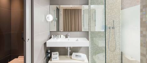 A modern bathroom with a toilet, a sink with a mirror, and a glass-enclosed shower area.
