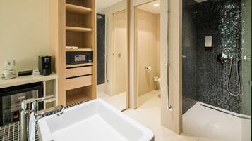 Un baño moderno con un lavamanos grande de color blanco, una ducha con cerramiento de vidrio y un mueble de tocador de madera con estantes.