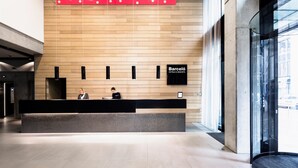 A hotel reception area with a modern design, featuring a wooden wall, a reception desk, and a sign for "Barceló Hotels & Resorts". - Barceló Hamburg (Hamburg)