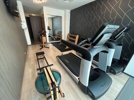 Ein modernes Fitnessstudio mit Laufband, Rudergerät und Gewichten.