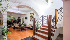 A spacious living area with a staircase, a sofa set, and a dining table. - Hotel Hacienda de Vallarta Centro (Puerto Vallarta)