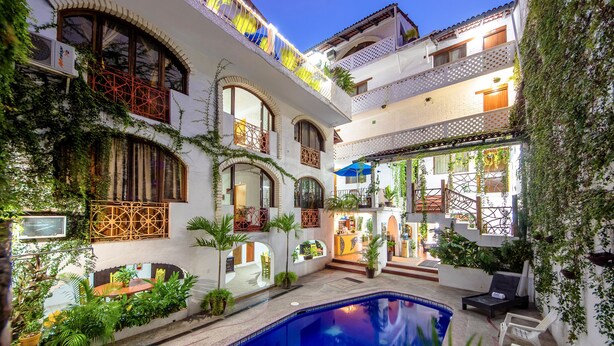 A courtyard with a swimming pool, outdoor seating, and multiple balconies with plants. - Hotel Hacienda de Vallarta Centro (Puerto Vallarta)