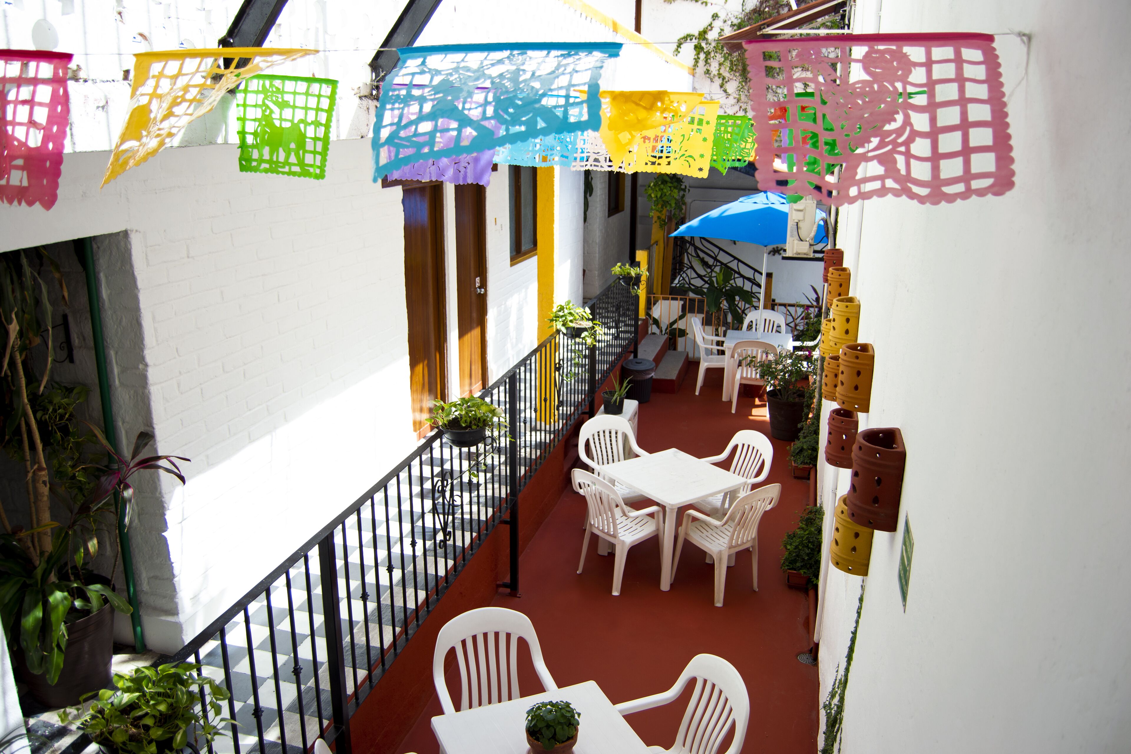 Ein Balkon mit weißen Korbmöbeln, Blumentöpfen und bunten Papierdekorationen.