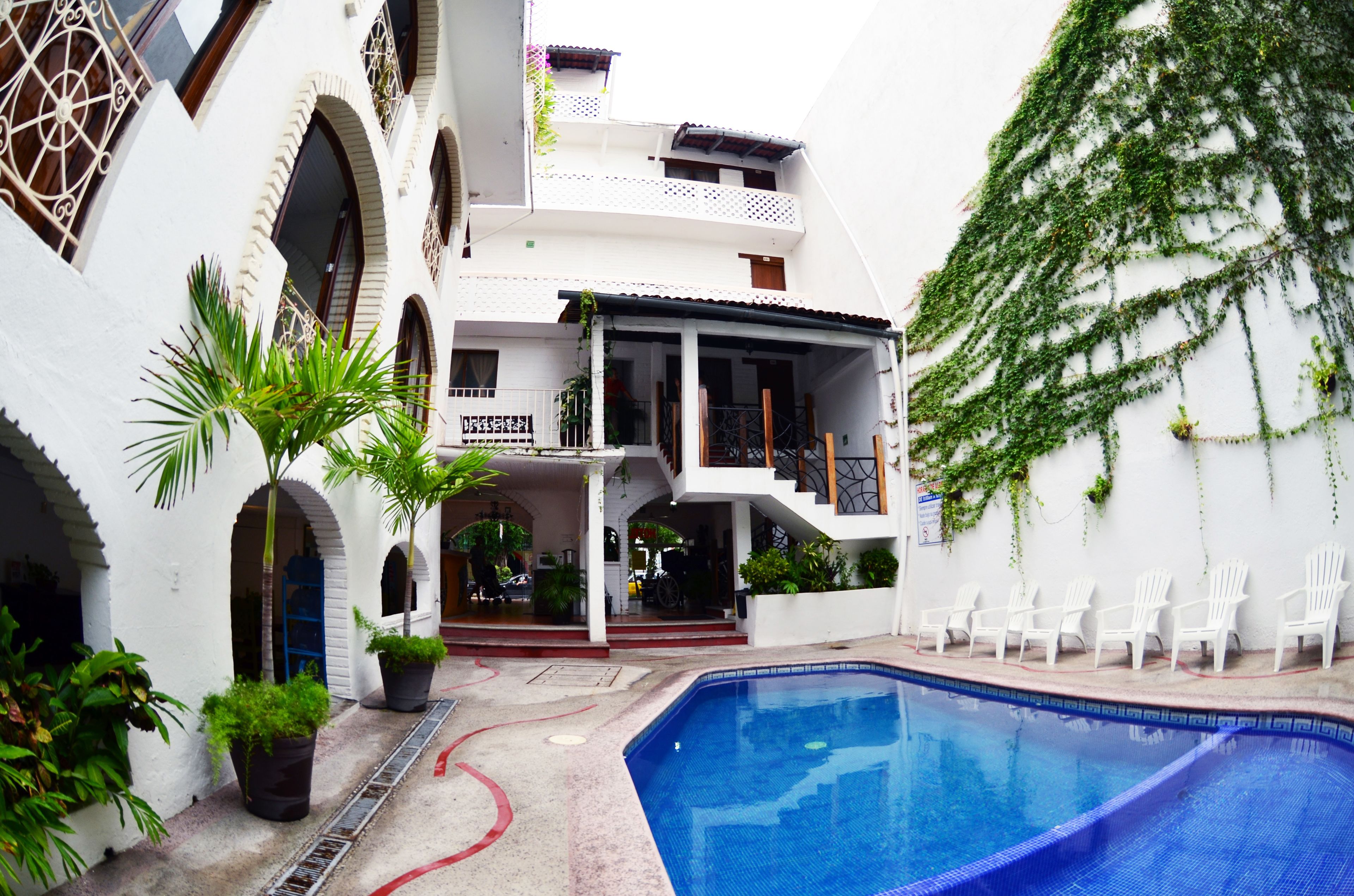 Um edifício branco com piscina e área de estar ao ar livre.
