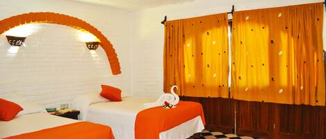 A hotel room with two beds, a checkered floor, and a brick wall.