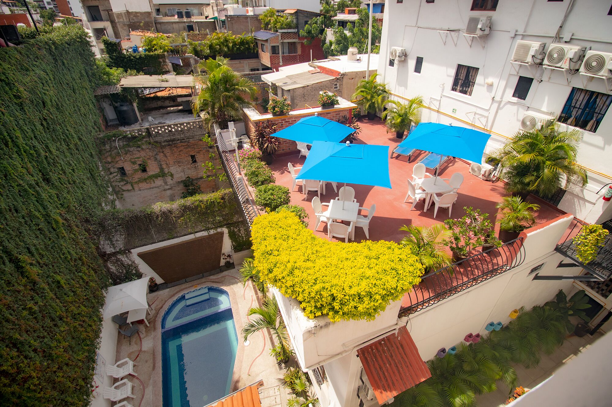 A rooftop patio with outdoor seating, a swimming pool, and surrounding greenery.