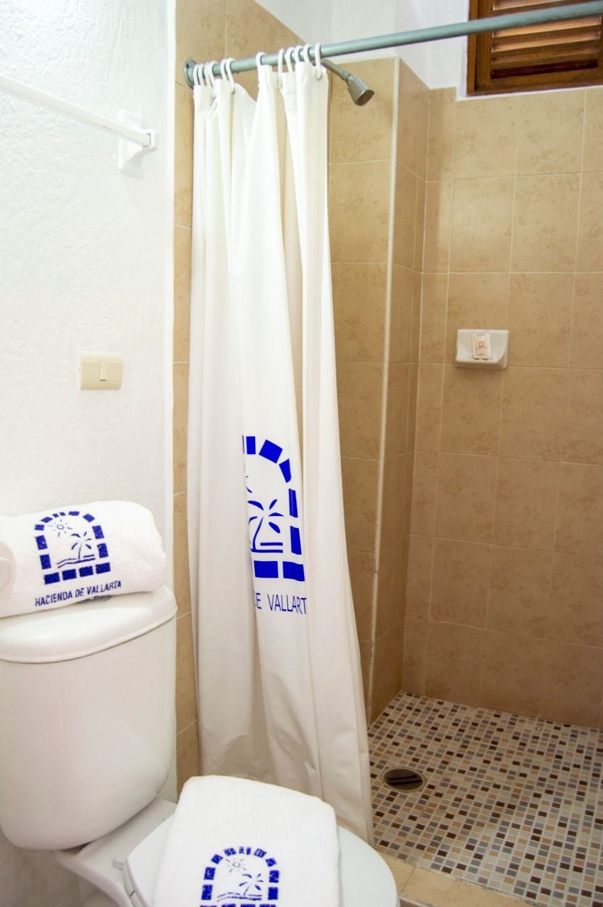 A bathroom with a shower curtain, a toilet, and a tiled floor.