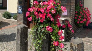 A hotel entrance with a sign reading "Hotel Altseefest." There are flower arrangements at the entrance, and a sign indicating "Boy" room type. - Alte Post (Fulpmes)
