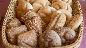 A basket filled with various types of bread, including rolls and seeded bread, placed on a table. - Alte Post (Fulpmes)