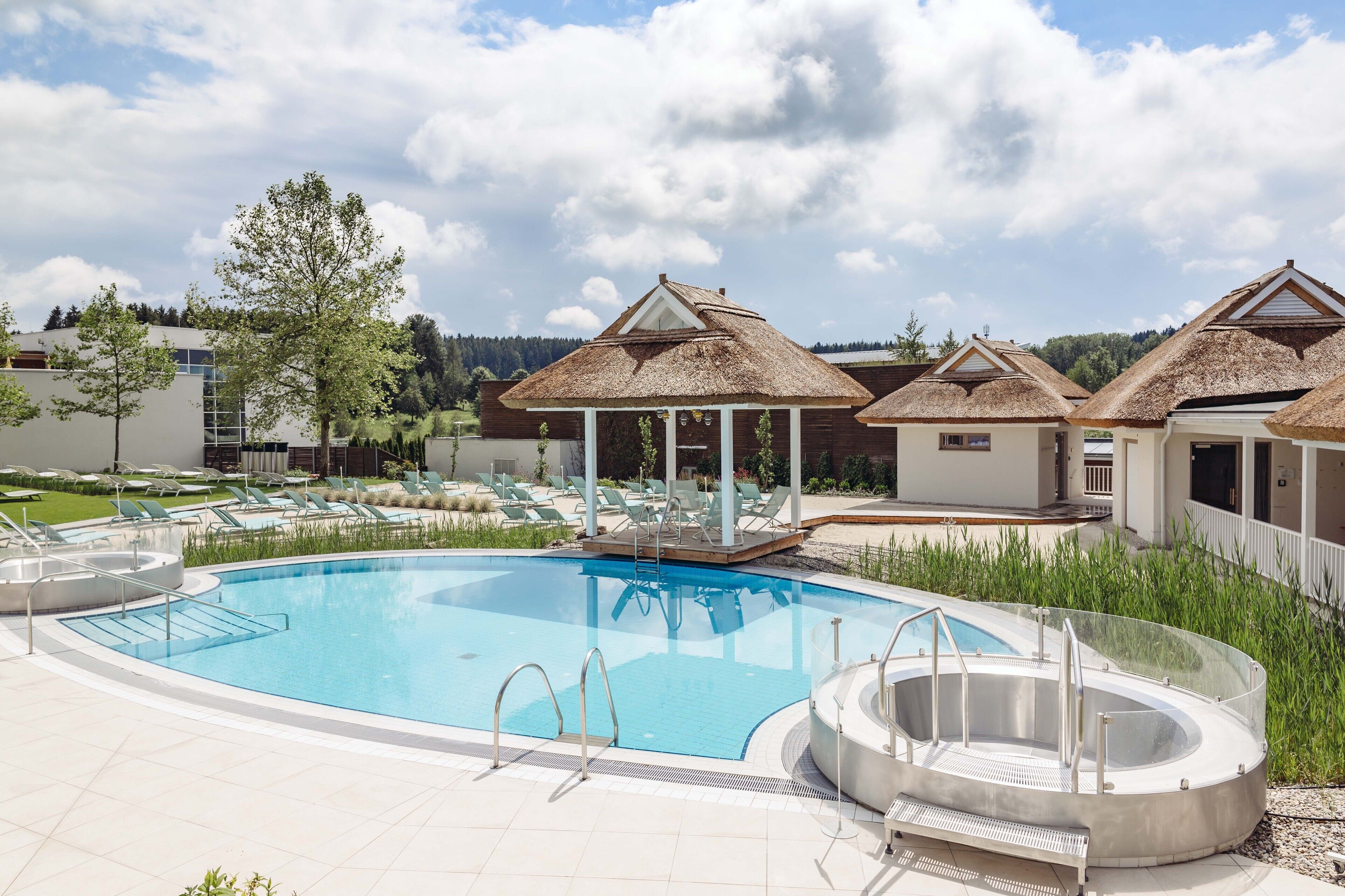 A swimming pool with lounge chairs and thatched-roof structures.