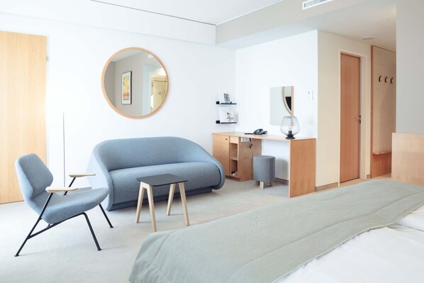 Una habitación de hotel moderna con cama, sofá, escritorio y silla.