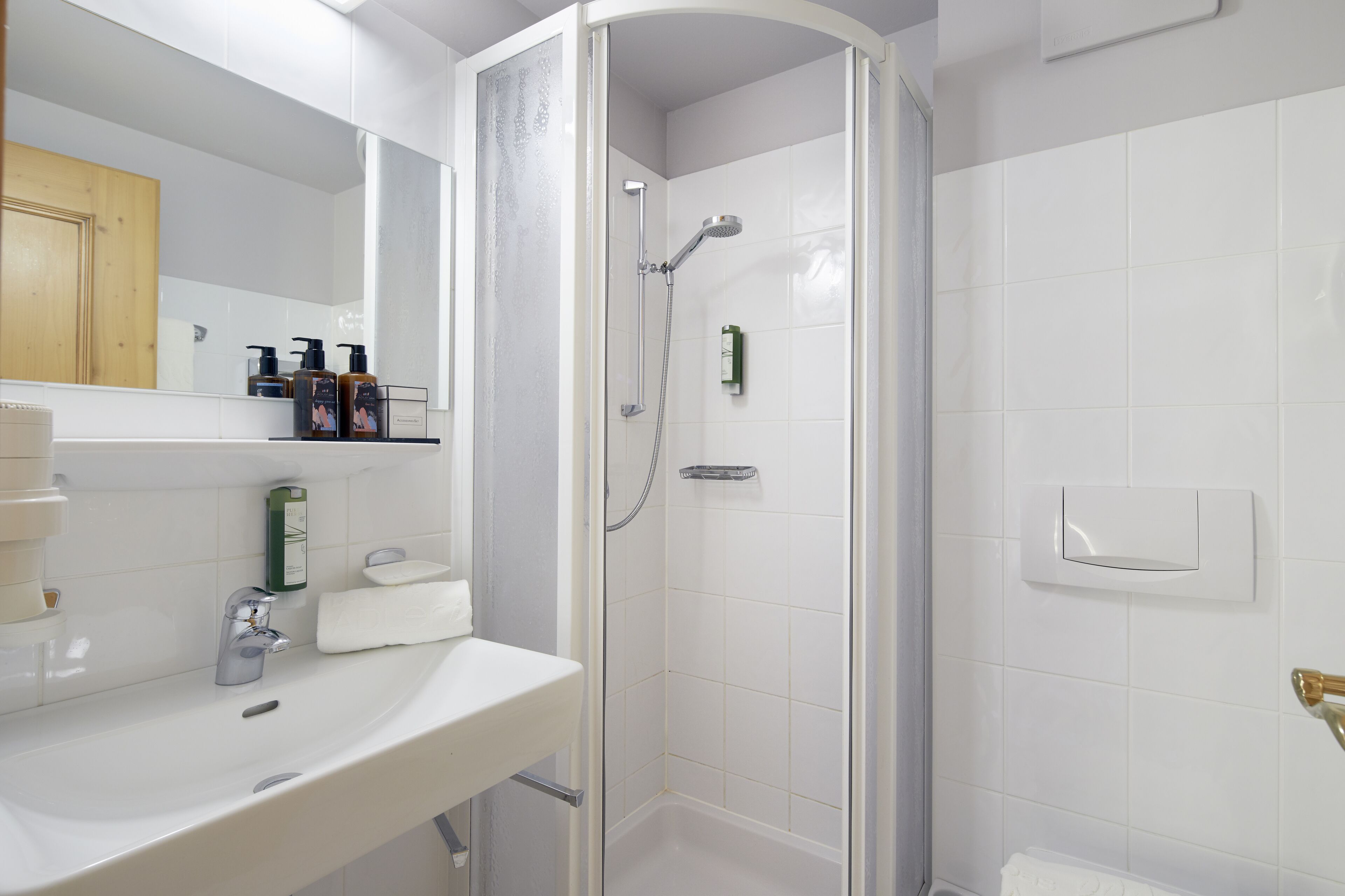 A modern bathroom with a white sink, a glass-enclosed shower, and a wooden cabinet.