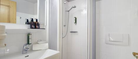 A modern bathroom with a white sink, a glass-enclosed shower, and a wooden cabinet.