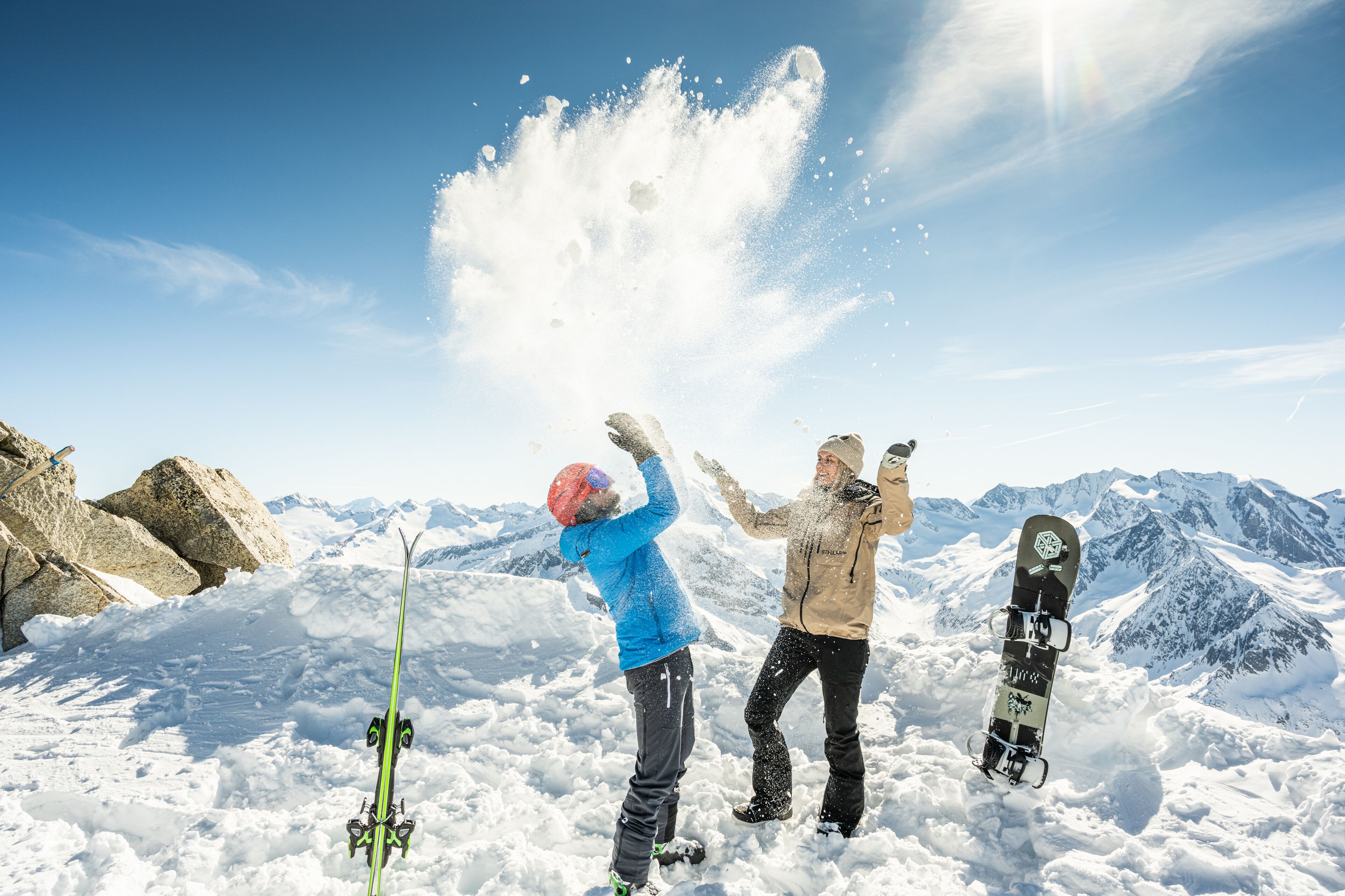 Un paisaje nevado de montañas con tres personas y una tabla de snowboard.