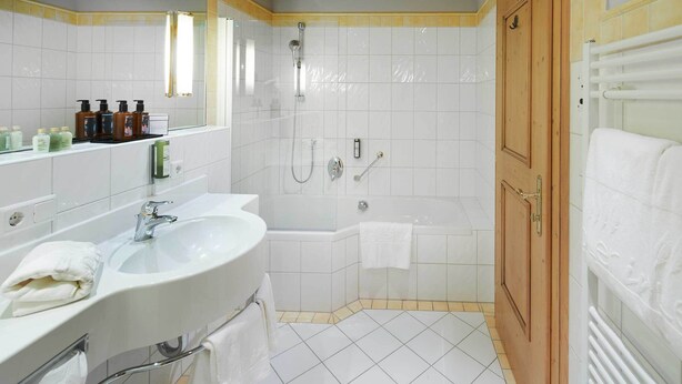 A bathroom with a sink, mirror, shower, and bathtub. - Adler Inn Tyrol Mountain Resort SUPERIOR (Tux)