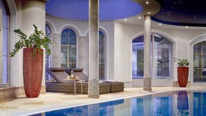 A luxurious indoor pool area with a seating area, large potted plants, and arched windows. - Adler Inn Tyrol Mountain Resort SUPERIOR (Tux)