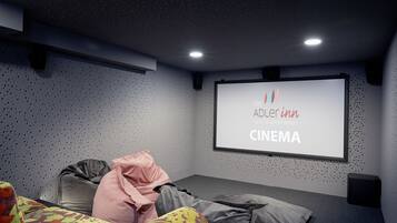 Uma sala de cinema em casa com uma tela grande exibindo 'Adler Inn Tyrol Mountain Resort CINEMA'.