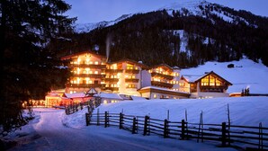 A snow-covered mountain resort with multiple buildings, including a large lodge with balconies and a smaller cabin. - Adler Inn Tyrol Mountain Resort SUPERIOR (Tux)