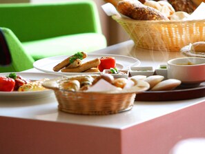 Een tafel met diverse etenswaren, waaronder brood, een rode tomaat en kleine schaaltjes met sauzen.