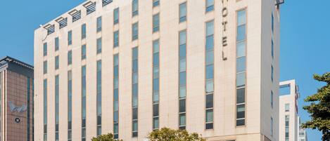 A modern hotel with a prominent 'ibis' sign, a clean facade, and a structured window pattern.