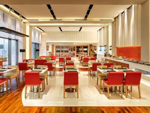 Un restaurant moderne doté de plusieurs espaces de restauration, d’un plancher en bois et d’un long comptoir où sont exposés les plats.