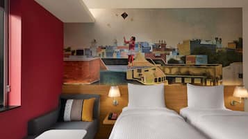 Une chambre d’hôtel avec une fresque représentant un paysage urbain, deux lits, un canapé et une petite table.
