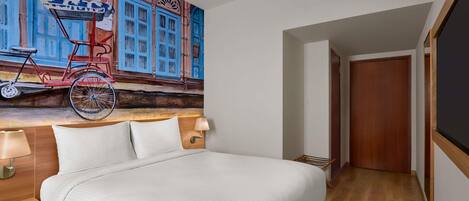 Habitación de hotel con cama, lámpara de pared, cabecero de madera y un mural de una bicicleta.
