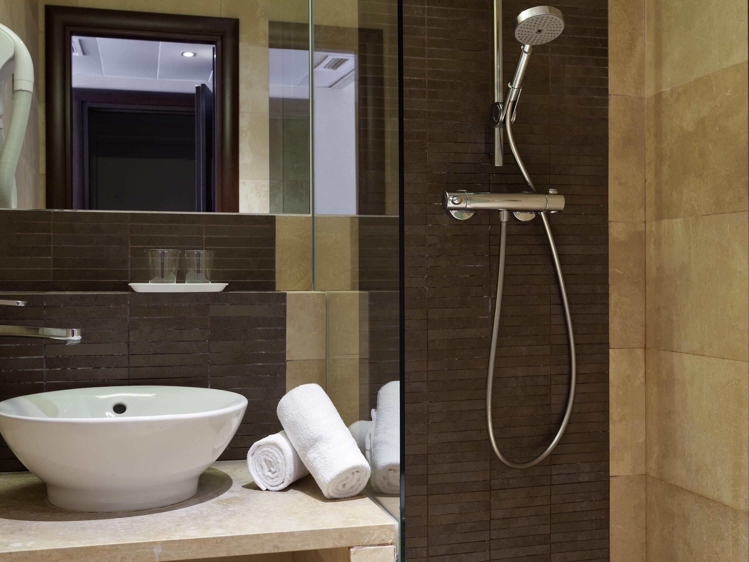 Un baño con lavamanos blanco, cabina de ducha de vidrio y un perchero para toallas.