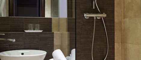 Un baño con lavamanos blanco, cabina de ducha de vidrio y un perchero para toallas.