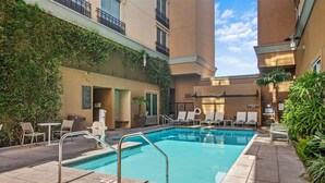 A pool area with lounge chairs, a pool, and a sign indicating an emergency exit.