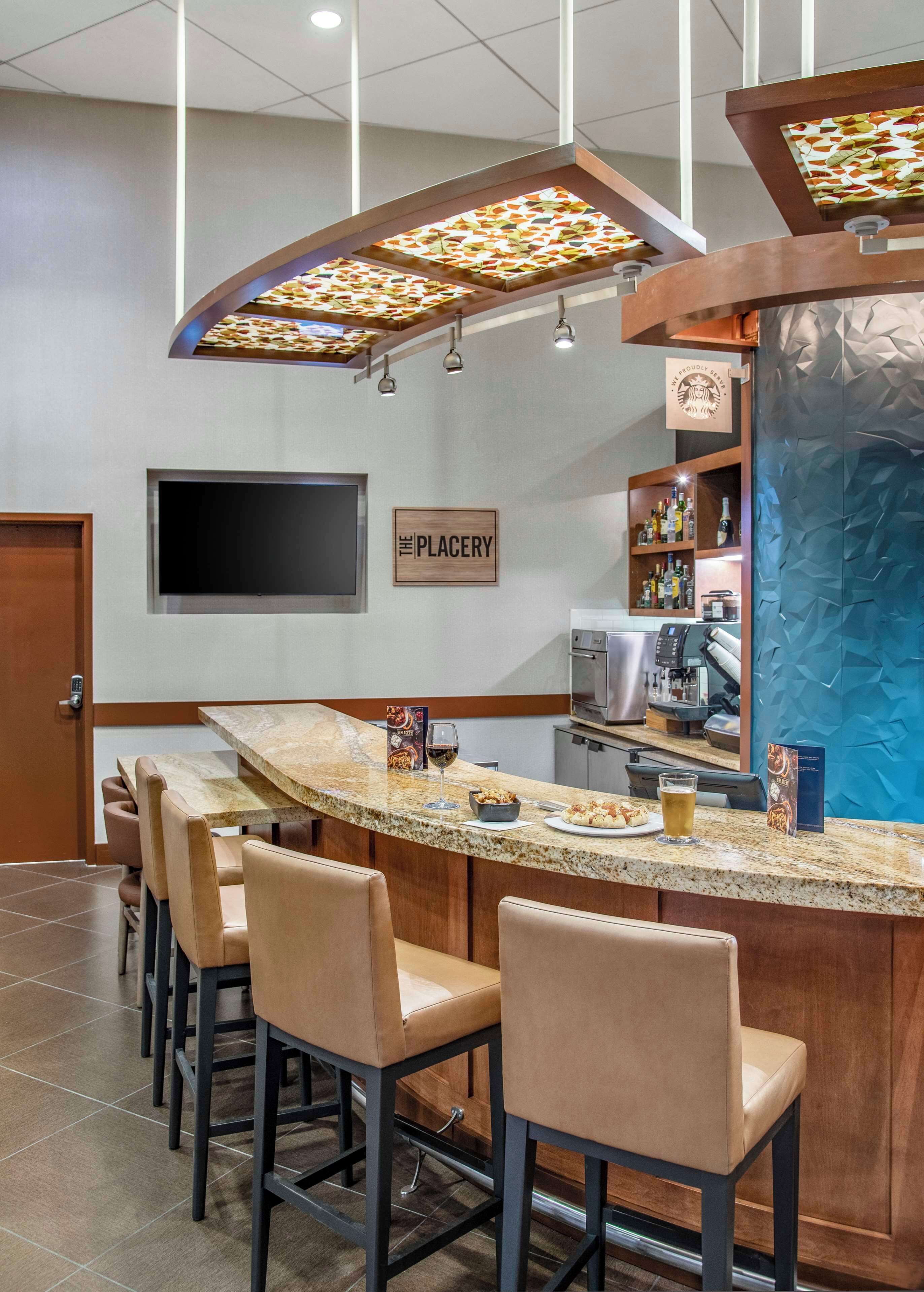 A bar area with a counter, bar stools, a coffee machine, and a sign that reads "The Placery".