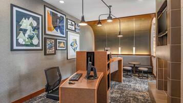 Habitación de hotel moderna con escritorio, computadora y zona de estar.
