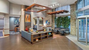 A modern lobby with a seating area, a reception desk, and a large window overlooking greenery.