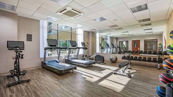Un gimnasio con cintas de correr, elípticas y pesas libres.