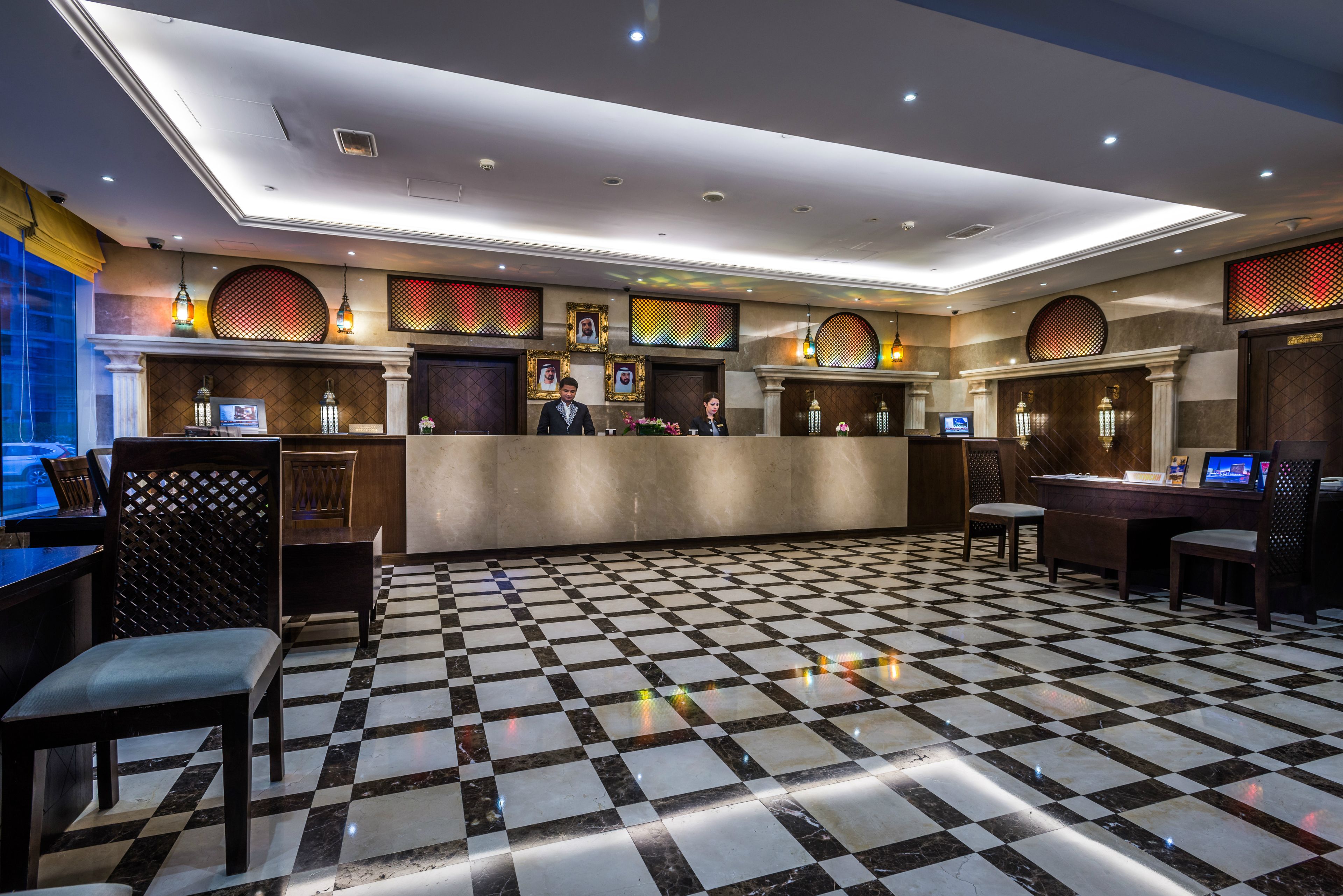 A hotel lobby with a checkered floor, reception desk, and seating area.