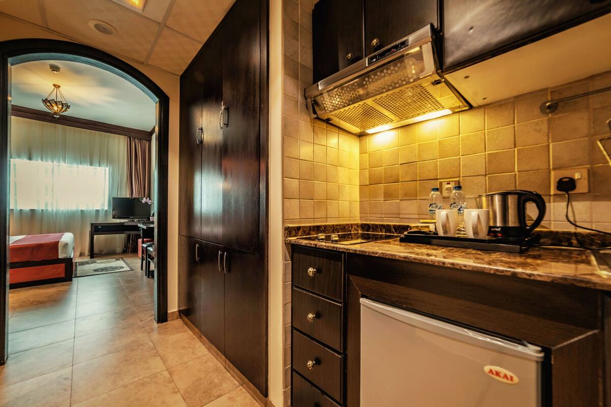 Eine kompakte Küche mit dunklen Holzausziehtüren, einem fest eingebauten Herd und einem kleinen Kühlschrank.