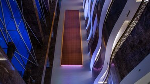 Un hall d’hôtel avec un sol à carreaux, un comptoir d’accueil et un escalier menant aux étages supérieurs.
