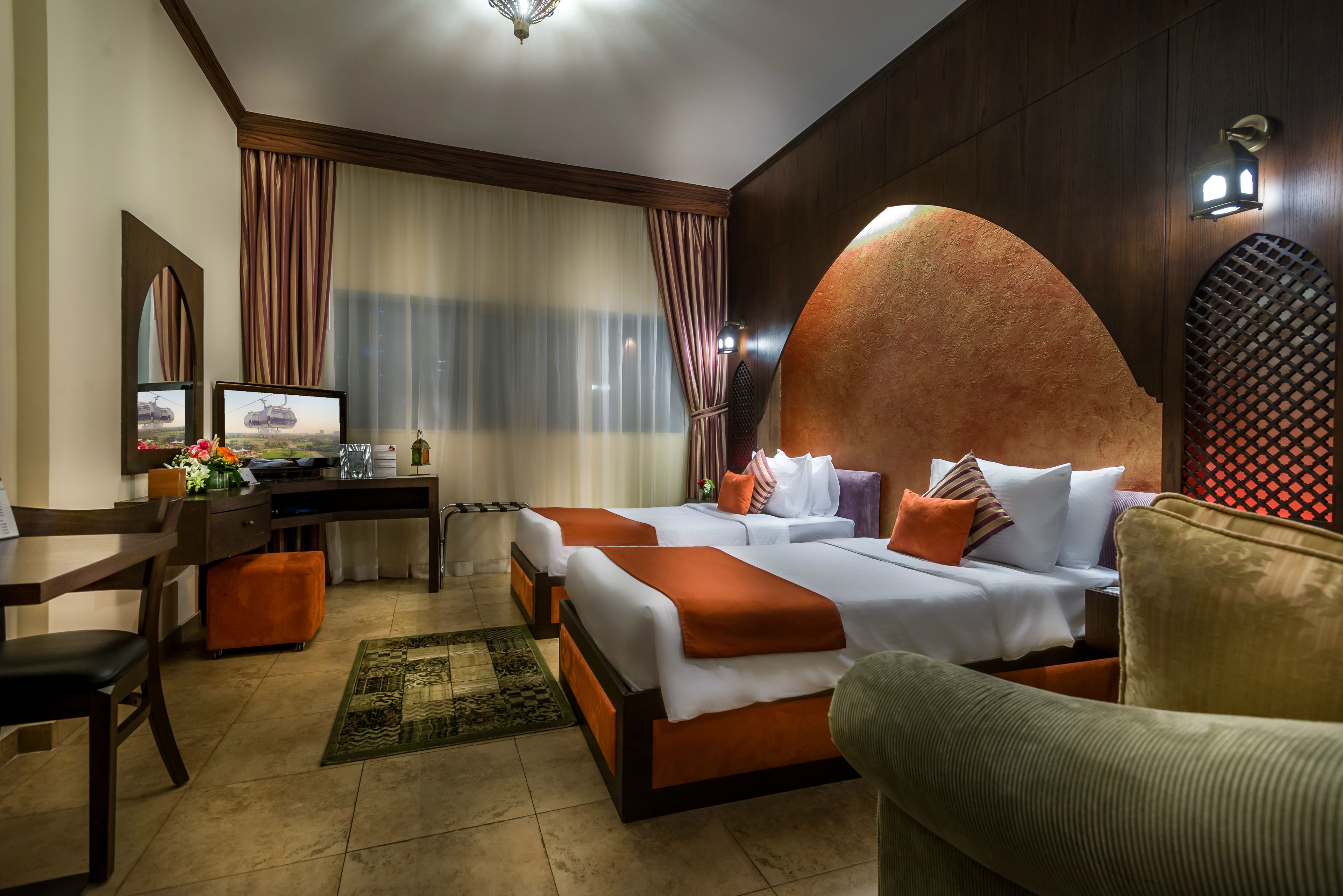 A hotel room with two beds, a desk, a chair, and a sofa.