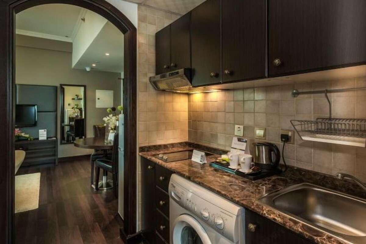 A modern kitchen with dark cabinets, a stainless steel sink, and a built-in washing machine.
