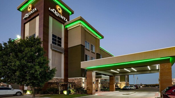 A hotel with a prominent tower featuring the name 'La Quinta' and a large parking area with a covered walkway. - La Quinta Inn & Suites by Wyndham Tulsa - Catoosa Route 66 (Catoosa)