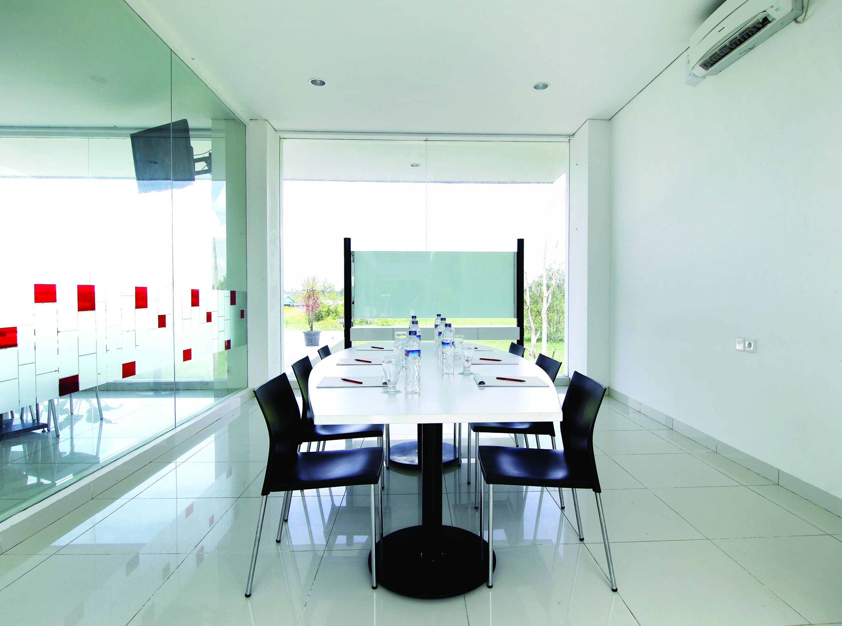 A conference room with a white table, black chairs, and a glass partition.