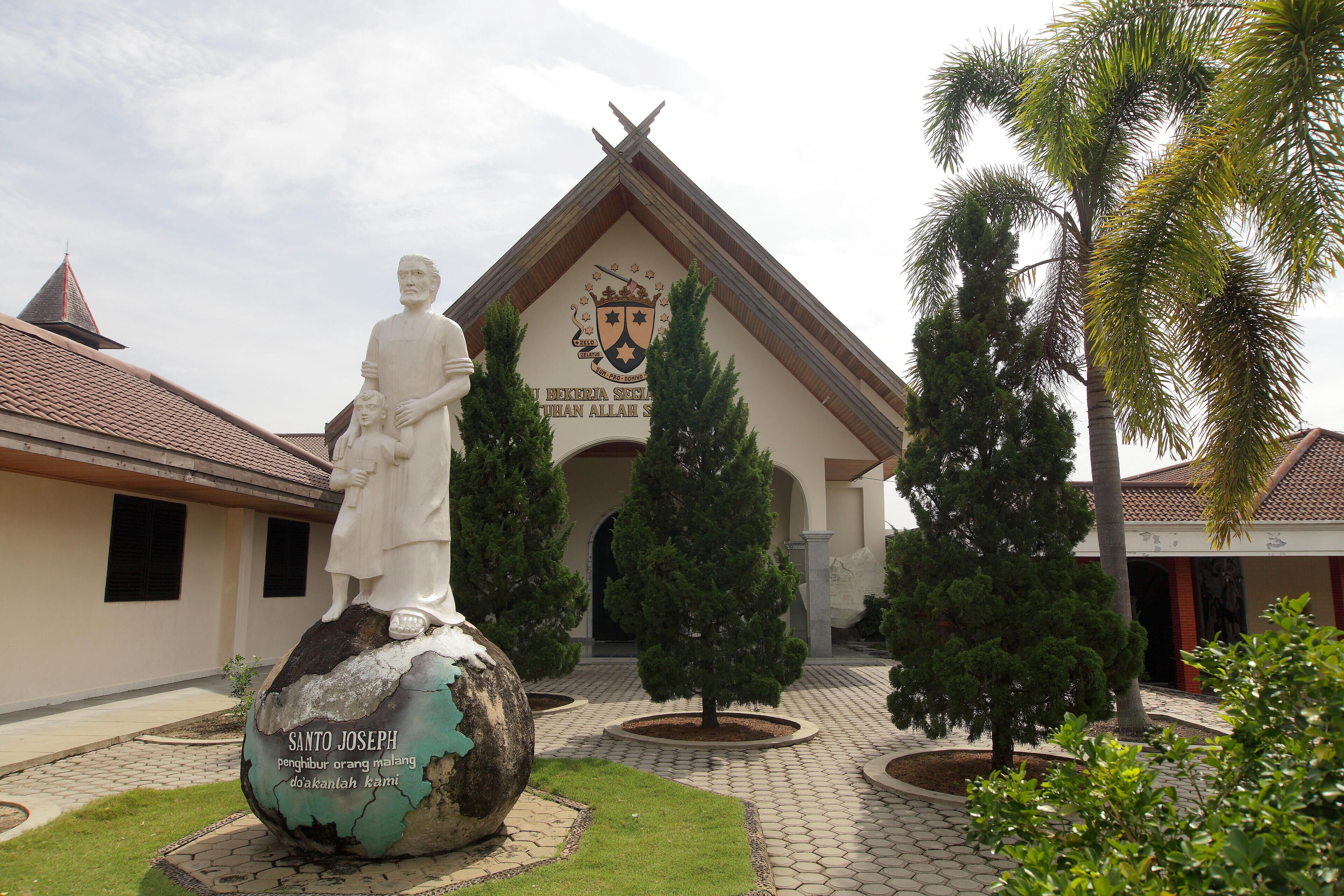 A statue of a man on a globe with a building in the background.