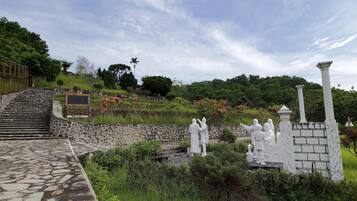 A stone pathway leading to a garden with statues and a stone wall.