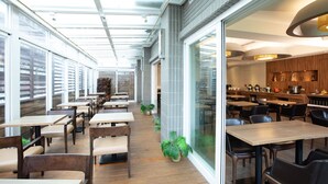 A modern restaurant with long tables and chairs, a glass wall, and a kitchen visible through the glass. -  Hotel Cloud-ZhongShan  (Taipei)