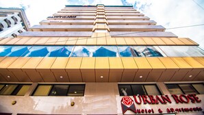 Un hotel con fachada moderna, varios balcones y un llamativo letrero que dice "URBAN ROSE Hotel & Apartments".