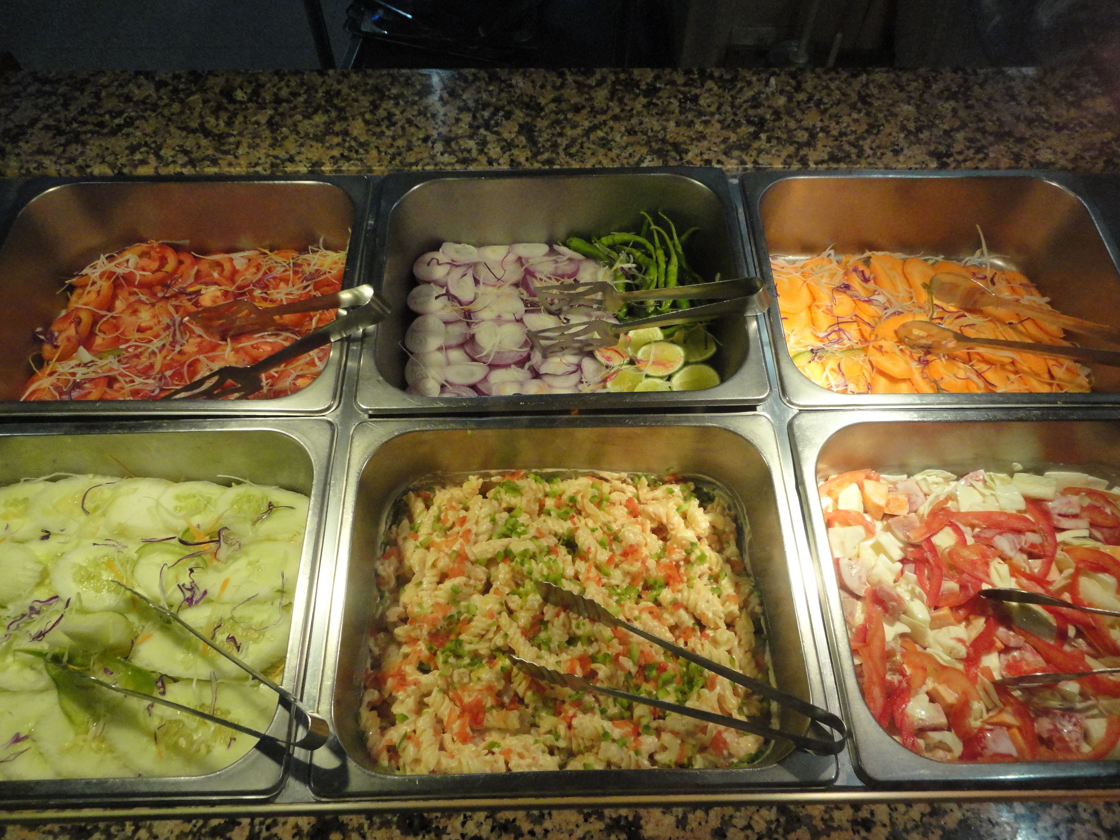Un buffet proposant une variété de plats, notamment des pâtes, des légumes et des fruits de mer.