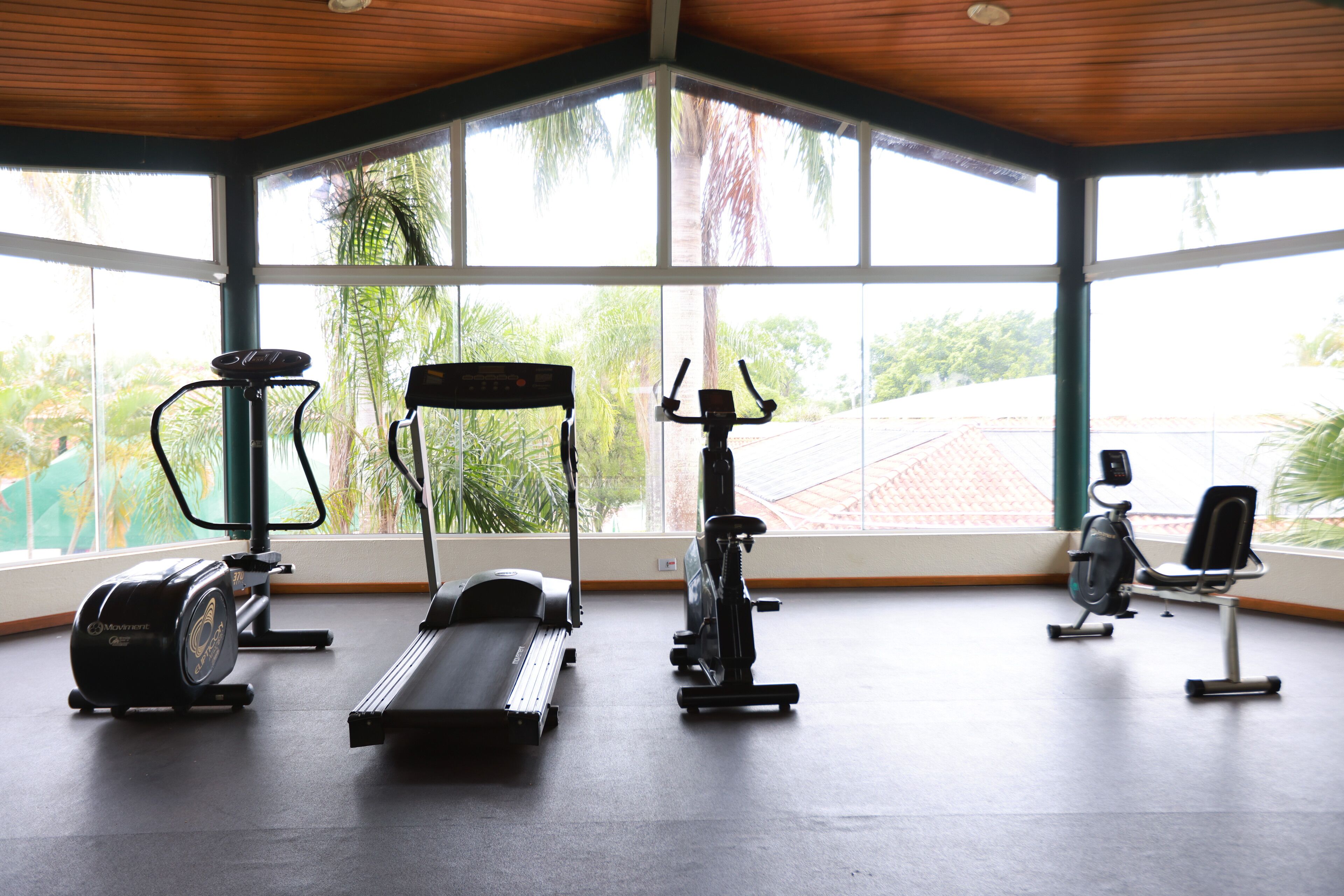 Un gimnasio con máquinas de cardio, una máquina de remo y una bicicleta estática.