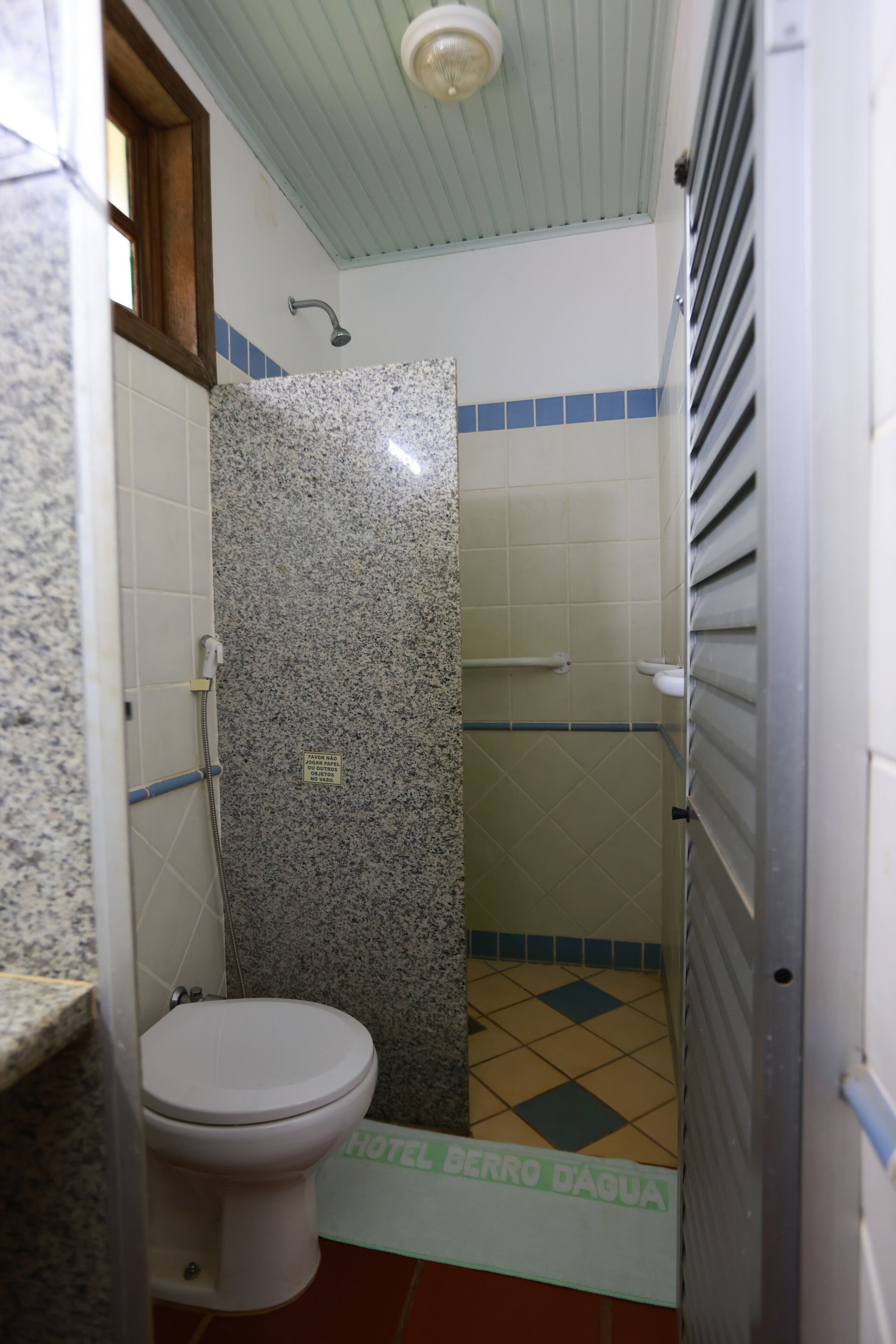 Een badkamer met toilet, douche en een betegelde vloer.