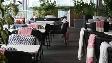 An outdoor seating area with wicker furniture and tables, some with blankets.